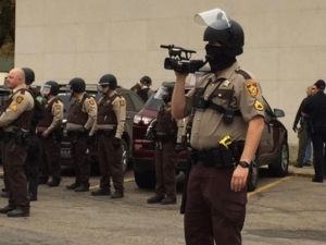 law enforcement officer wearing a mask, holding a video camera