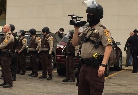 law enforcement officer wearing a mask, holding a video camera